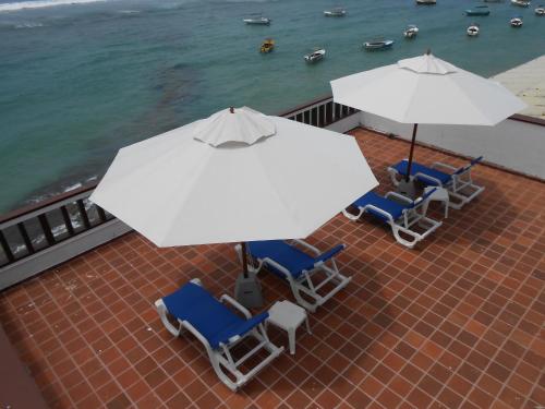 a group of chairs and umbrellas on a patio near the water at Coral Seas Beach Hikkaduwa in Hikkaduwa