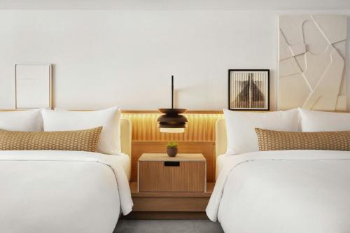 a hotel room with two beds and a table between them at The Jay, Autograph Collection in San Francisco