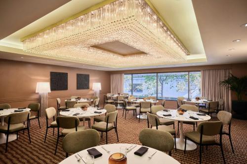 a restaurant with tables and chairs and a large chandelier at The Jay, Autograph Collection in San Francisco