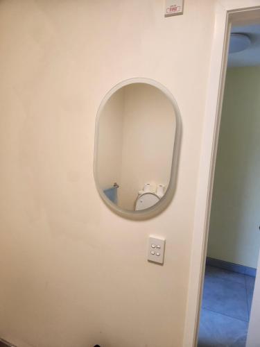 a round mirror on a white wall in a room at The White House Apartment in Tokoroa
