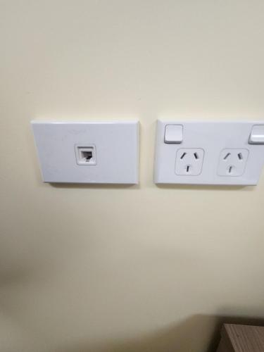 a lightswitch on a wall with two faces on it at The White House Apartment in Tokoroa