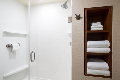 a bathroom with a glass shower door with towels at Courtyard by Marriott Maui Kahului Airport in Kahului