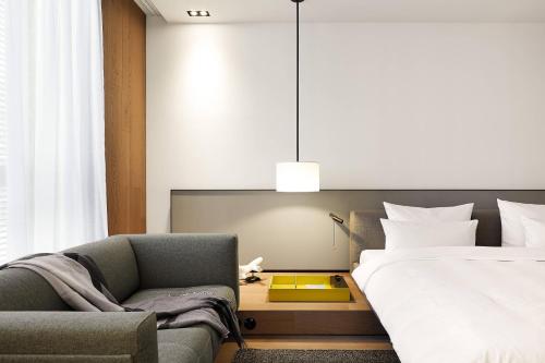 a bedroom with a bed and a couch and a chair at Roomers Baden-Baden, Autograph Collection in Baden-Baden