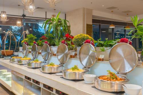 um buffet com comida servida em recipientes de aço inoxidável em Starcity Hotel & Condotel Beachfront Nha Trang em Nha Trang