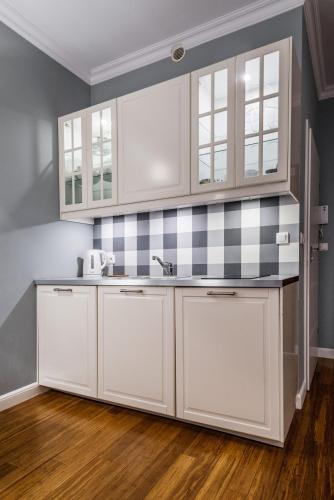 a kitchen with white cabinets and black and white tiles at Triton Park Apartments in Warsaw