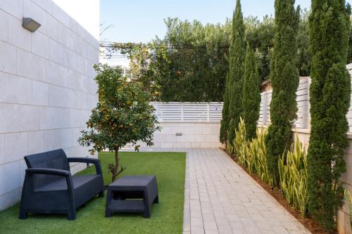 a small garden with a chair and an orange tree at Balfour sea view city center in Nahariyya