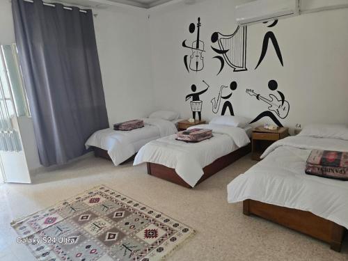 een slaapkamer met 3 bedden en een tapijt bij Lukanda Apartment Feel at Home in Amman