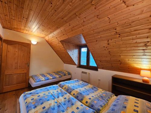 a bedroom with two beds and a wooden ceiling at Mlyn Vlachy 1997 in Vlachy