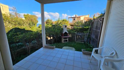 une terrasse couverte avec une chaise et une cour avec un phare dans l'établissement LA PALGE Le Centuri, à Linguizzetta