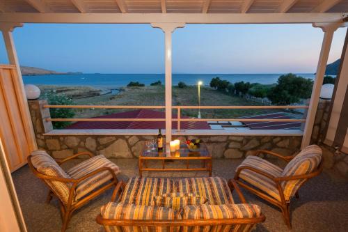 een veranda met een tafel en stoelen en uitzicht op de oceaan bij Evgatis Hotel in Kondiás