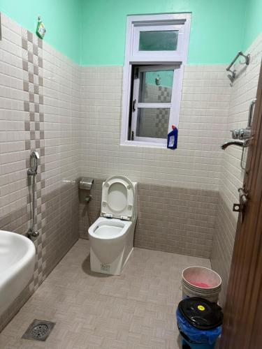 a bathroom with a toilet and a sink and a window at Sisters Home & Apartment in Kathmandu
