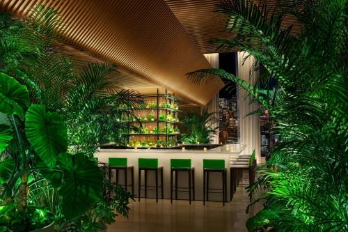 a lobby with green plants and a bar with stools at The Tokyo EDITION, Toranomon in Tokyo