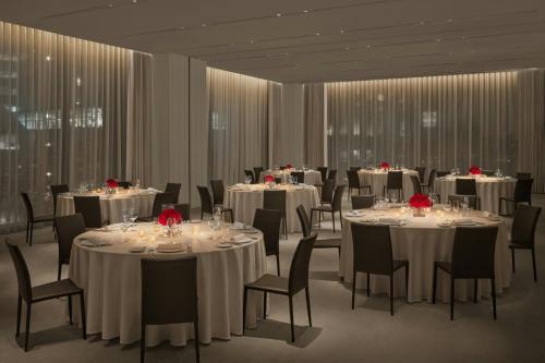 a conference room with tables and chairs with red roses on them at The Tokyo EDITION, Toranomon in Tokyo