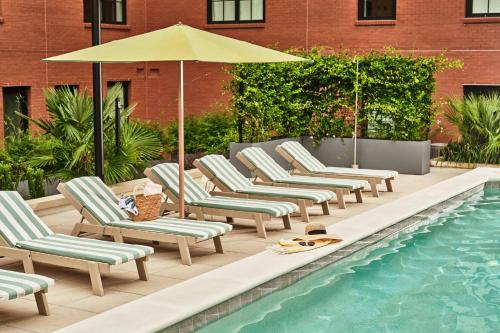 a row of chaise lounge chairs next to a swimming pool at The Ann Savannah, Apartments by Marriott Bonvoy in Savannah