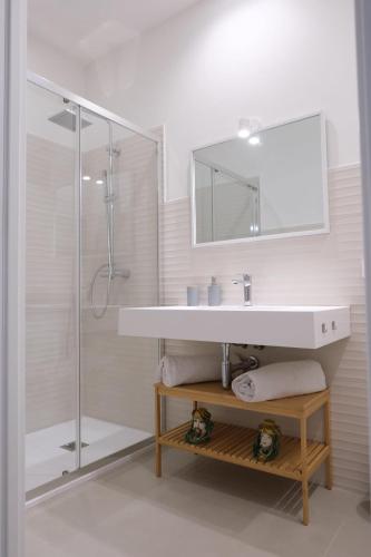 a white bathroom with a sink and a shower at Temples and Sea view Apartment in Agrigento