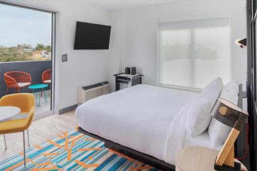 a bedroom with a bed and a balcony with a tv at Aloft Fort Lauderdale Airport & Cruise Port in Fort Lauderdale