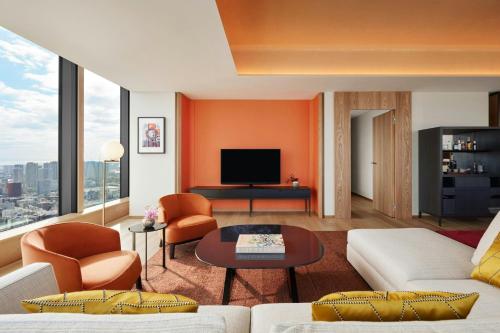a living room with orange and white furniture and a tv at Bvlgari Hotel Tokyo in Tokyo