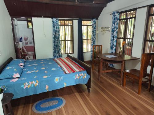 a bedroom with a bed and a table and a desk at PATTERI TRANQUILITY Homestay in Haripād
