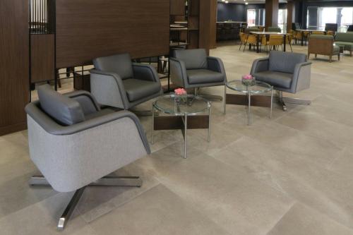 a waiting area with chairs and tables in a lobby at Courtyard Monterrey Airport in Monterrey