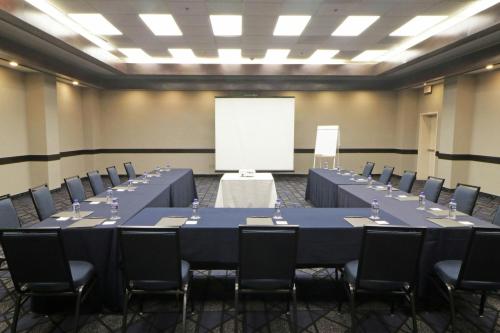 a conference room with tables and chairs and a white screen at Courtyard Monterrey Airport in Monterrey