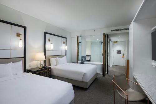 a hotel room with two beds and a bathroom at The Laura Hotel, Houston Downtown, Autograph Collection in Houston