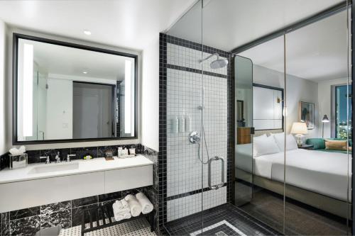 a bathroom with a shower and a sink and a bed at The Laura Hotel, Houston Downtown, Autograph Collection in Houston