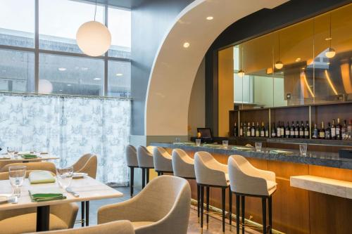 a restaurant with tables and chairs and a bar at The Laura Hotel, Houston Downtown, Autograph Collection in Houston