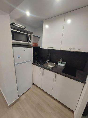 une petite cuisine avec un évier et un micro-ondes dans l'établissement Appartement avec terrasse dans la verdure, à Rueil-Malmaison