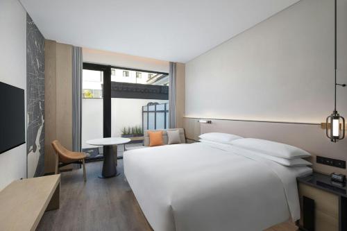 a bedroom with a large white bed and a table at AC Hotel by Marriott Suzhou, Guan Qian in Suzhou