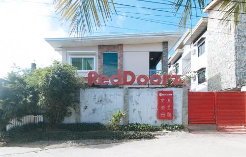 a red door sign in front of a house at RedDoorz Hostel @ St. Paul Village LapuLapu in Mactan