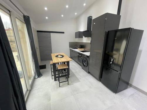 Il comprend une cuisine équipée d'une table et d'un réfrigérateur noir. dans l'établissement Maison à la campagne au bord de la ville, à Préguillac