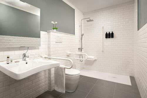 a white bathroom with a sink and a toilet at Duo Milan Porta Nuova, a Tribute Portfolio Hotel in Milan