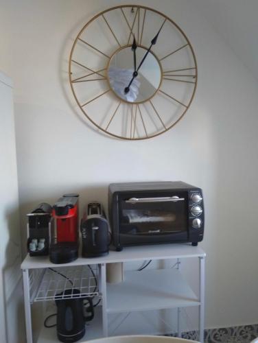 - une horloge sur le mur au-dessus d'un four micro-ondes et d'un grille-pain dans l'établissement L'horizon de Trouville - Studio, à Trouville-sur-Mer