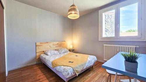 une chambre avec un lit, une table et une fenêtre dans l'établissement La Comète 4 Bedroom WiFi TV, à Saint-Étienne