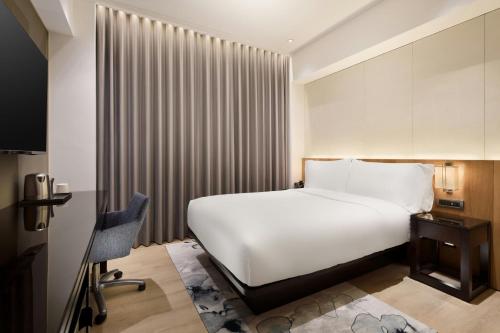 a hotel room with a white bed and a desk at Aloft Taipei Zhongshan in Taipei
