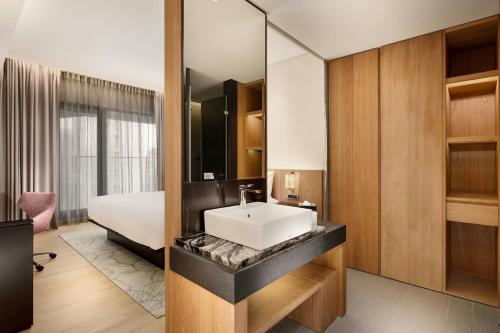 a bathroom with a sink and a bed at Aloft Taipei Zhongshan in Taipei