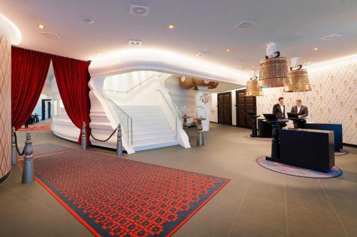 a lobby with a staircase and two men sitting at a desk at Kameha Grand Zurich, Autograph Collection in Glattbrugg