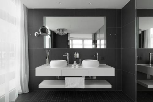 a bathroom with two sinks and a large mirror at Kameha Grand Zurich, Autograph Collection in Glattbrugg