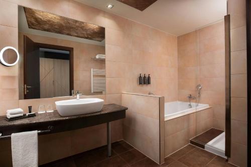 a bathroom with a sink and a tub and a mirror at Sheraton Milan Malpensa Airport Hotel & Conference Centre in Ferno