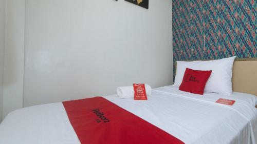 a bed with red and white pillows on it at RedDoorz Hostel @ St. Paul Village LapuLapu in Mactan