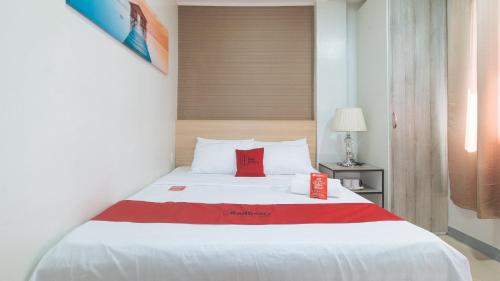 a bedroom with a white bed with a red box on it at RedDoorz Hostel @ St. Paul Village LapuLapu in Mactan