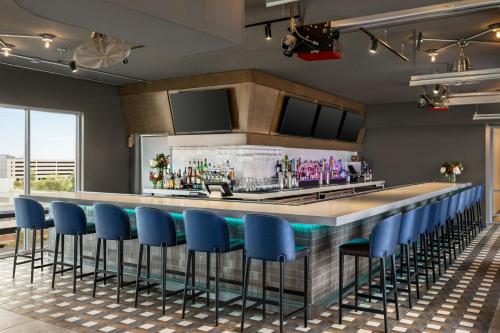 a bar with blue bar stools in a room at Aloft Wilmington at Coastline Center in Wilmington