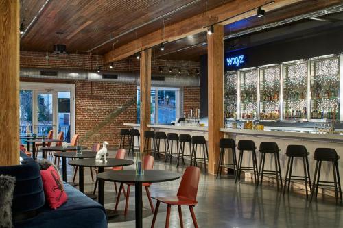 a restaurant with tables and chairs and a bar at Aloft Wilmington at Coastline Center in Wilmington