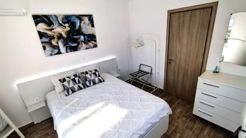 a white bedroom with a bed and a dresser at Angelica Residence in Gennadi