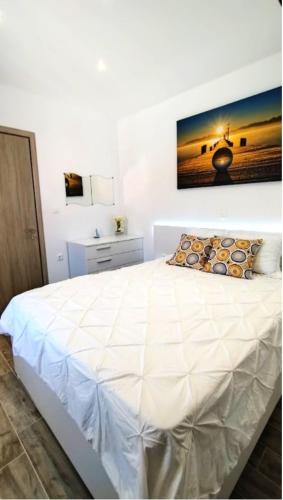 a bedroom with a white bed with a picture on the wall at Angelica Residence in Gennadi