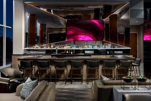 a bar at a hotel with leather chairs and a bar counter at AC Hotel by Marriott San Francisco Airport/Oyster Point Waterfront in South San Francisco