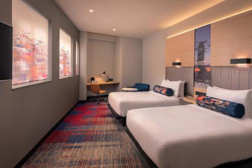 a hotel room with two beds and a desk at Aloft Madrid Gran Via in Madrid