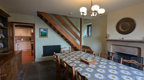 a dining room with a table and a staircase at Keeper’s Cottage in Montacute