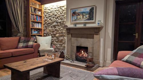 a living room with a fireplace and a table at Keeper’s Cottage in Montacute