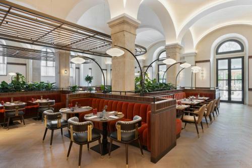 a restaurant with tables and chairs in a room at Imperial Riding School, Autograph Collection in Vienna